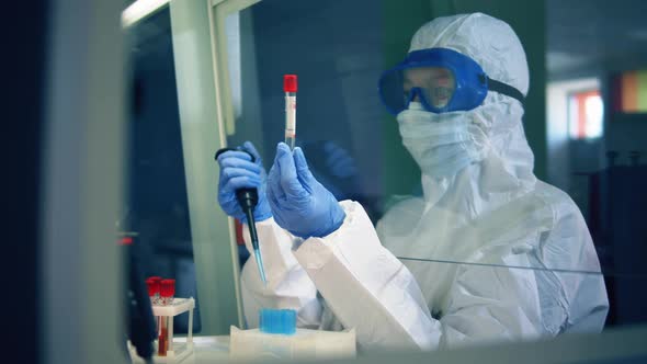 Female Lab Worker in a Splash Suit Is Examining a Test Tube alt