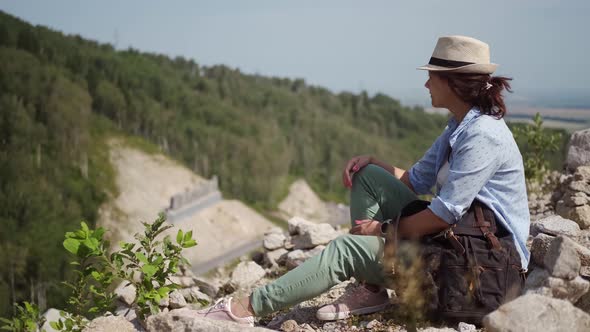 Woman Traveler Resting Sitting on the Edge of a Cliff. Hiker in the Mountains alt
