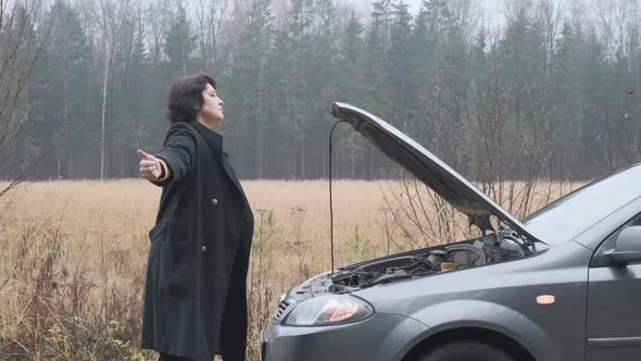 Woman Stands By the Road Near a Broken Car
