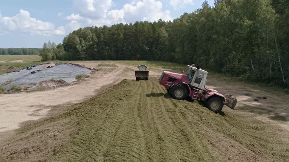 Drone view of tractors tamp the silage in the Silo Trench next to the forest 09 alt