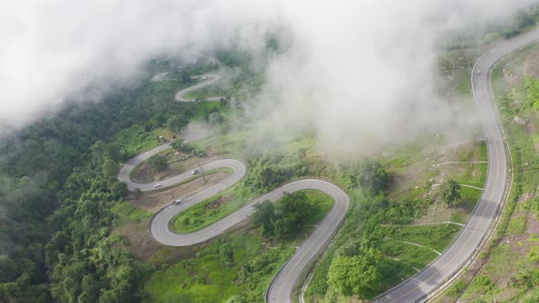 Aerial view of cars driving on curved, zigzag curve road or street on mountain hill
