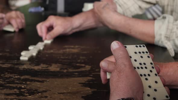 Senior Hands Playing Game of Domino Holding Dominoes Pieces or Blocks