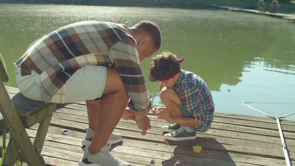 Family of Fishermen Putting Baits on Hooks to Fish with Fishing Rod on Pond alt