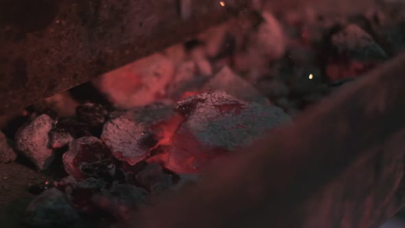 Closeup of Hot Coals in the Grill are Smashed with a Poker alt