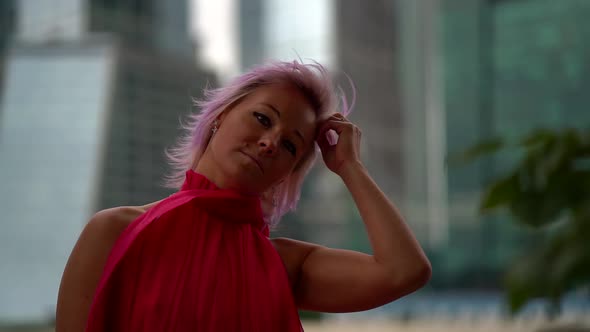 Portrait of an Unusual Woman with Pink Hair Posing in the Afternoon on the Street Against the alt