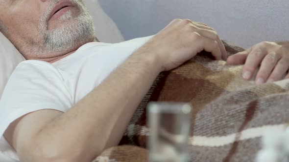 Aged Man Sleeping on Bed with Glass Standing in Front, Drugs for Insomnia alt