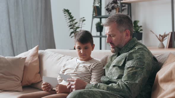 Army Veterain in Uniform Showing Photos to Son alt