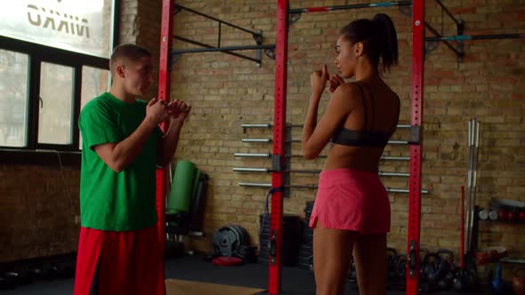 Male Boxing Trainer Showing Slipping Technique to African Female Boxer at Gym alt