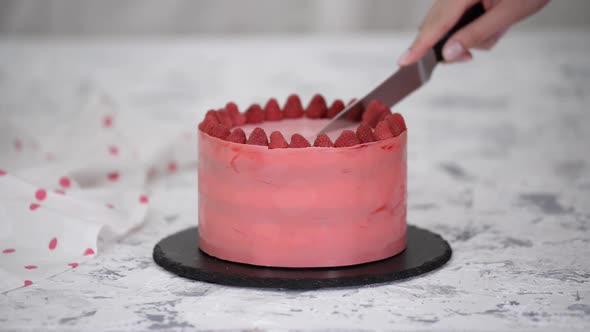 Closeup of Woman Confectioner Cutting a Raspberry Cake