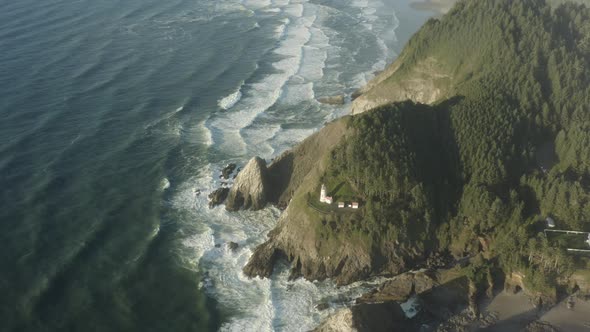 Wide aerial of Haceta Head lighthouse pulling back to reveal vast coastline alt