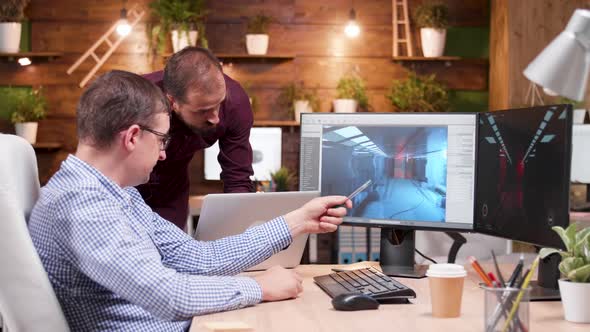 Graphic Desginer Working in Gaming Industry Showing His Assitant the New Game Design alt