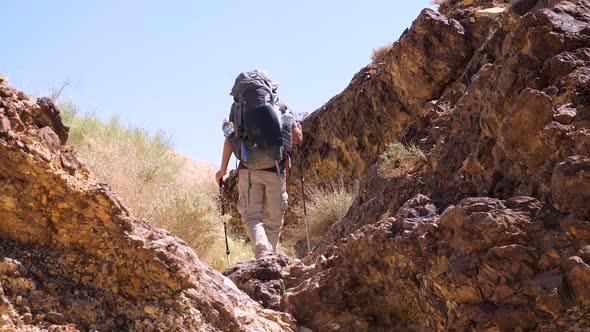 Static shot of alone hiker with a hiking pack, going around Crater Ramon, Negev desert in Israel on alt