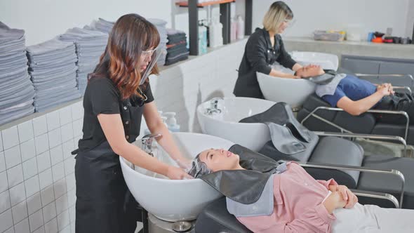 Asian young beautiful woman customer getting hair washed in hair beauty salon by hairdresser stylist alt