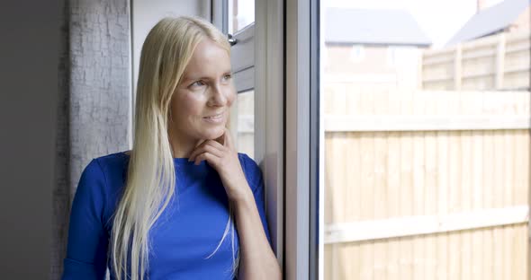 Smiling blond woman looking out of window