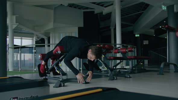 Young man is engaged in crossfit, doing leg exercises, warming up, in the gym.