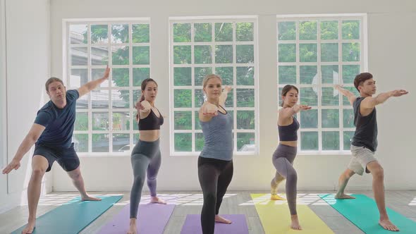 Group of sporty people practicing yoga lesson in fitness studio