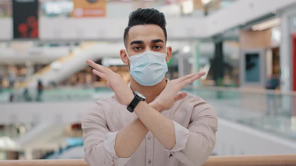 Young Hispanic Guy in Medical Mask Show Forbidding Gesture Serious Arab Man in Respirator Stand in alt