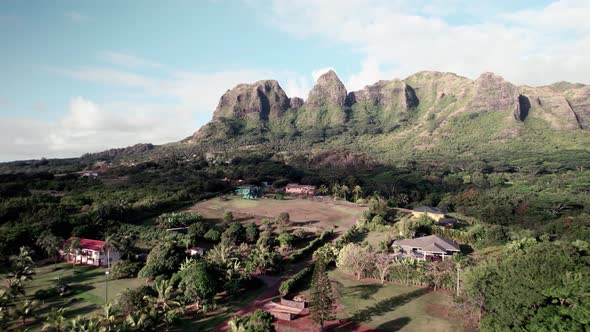 Residential homes spread out below jagged mountains in rural tropical Kauai, north shore, aerial alt