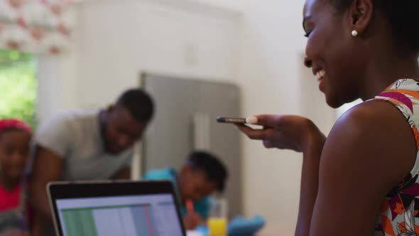 African american woman talking on smartphone while working from home alt