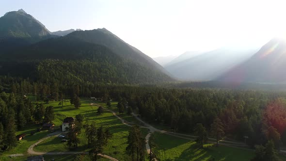 Green Forest and Mountains Against the Backdrop of Sunset or Dawn alt