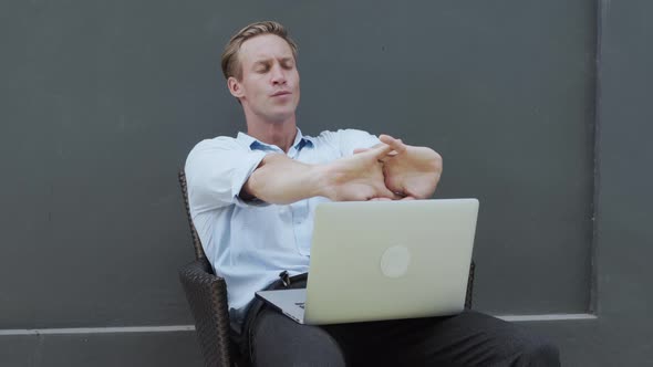Man Works with Laptop Stretching Arms Relaxing Body Grey Wall on Background alt
