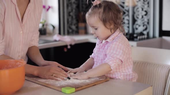 Little Girl Cooking with Caring Mother at Kitchen