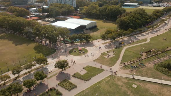 Aerial orbiting view of a roundabout in Vicente Lopez coastal walk and a sport club behind alt