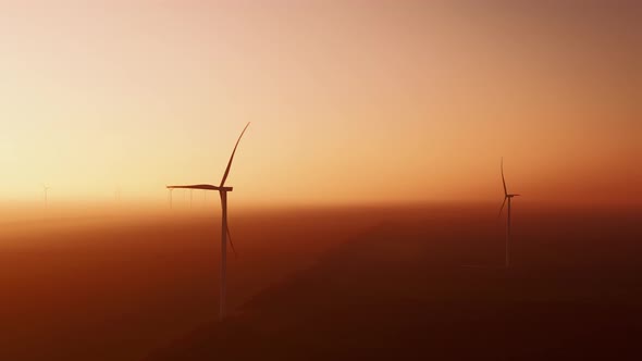 Offshore Wind Turbines Covered with Fog Rotate at Sunset