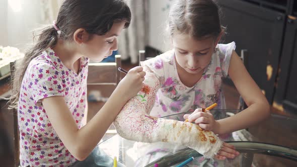 Caring Child Paints with a Bright Color a Plastered Hand To His Sister. alt