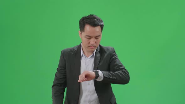 Asian Business Man Walking While Looking At Watch And Run On Green Screen Chroma Key alt