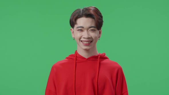 Smiling Asian Transgender Male Looking At Camera In The Green Screen Studio alt