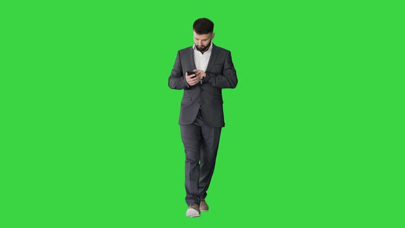 Businessman Walking and Using the Phone on a Green Screen, Chroma Key. alt