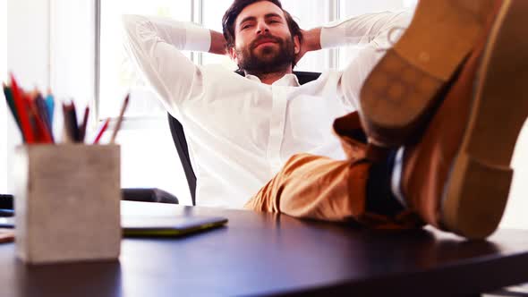 Male executive sitting with legs on table alt