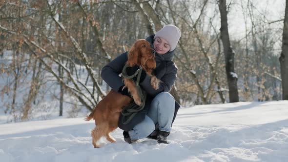 Young Woman Sitting Face to Face Playing with Her Spaniel Dog in Winter Park alt