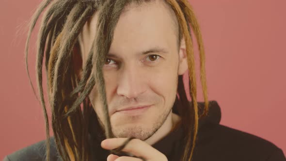 Young Man Twisting Hair and Looking at Camera on Pink Background alt