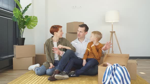 Happy Beautiful Family Relaxing on Floor While Moving Into New House
