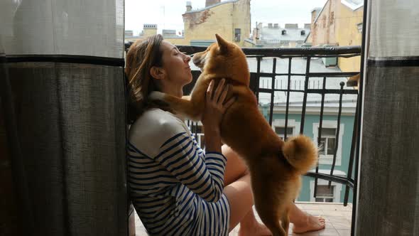 Attractive Young Woman is Sitting Home Together With Adorable Puppy Dog Shiba Inu