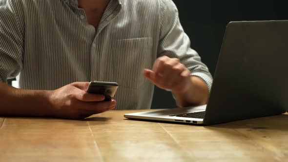 Man using smartphone and laptop alt