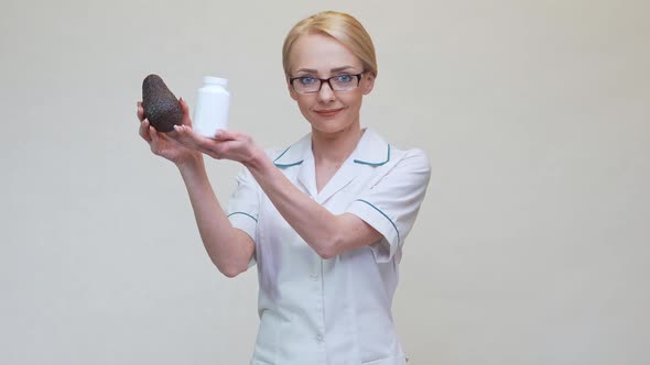 Nutritionist Doctor Holding Organic Avocado Fruit and Jar of Medicine or Vitamin or Omega 3 Capsules alt