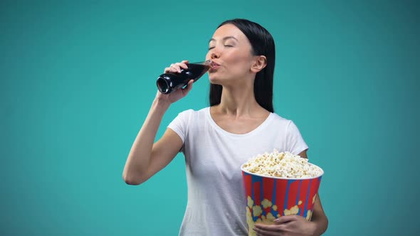 Asian Woman Holding Big Paper Cup With Popcorn and Drinking Soda Visiting Cinema alt