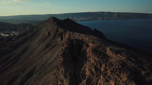 Drone View of Man on Motorbike Extremely Rides Across the Hills with Black Sea on Background in