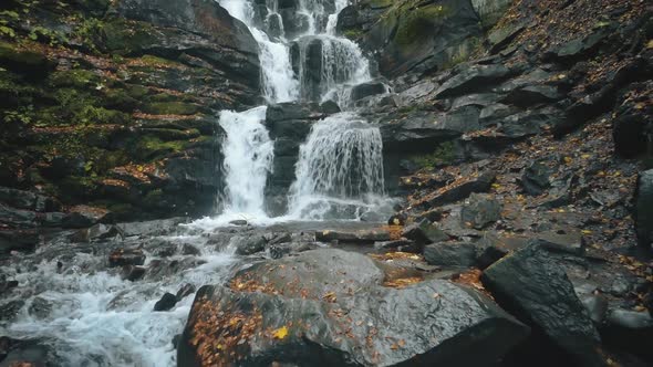 Foaming Water Falls Near Large Grey Rocks in Autumn