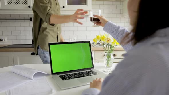 Couple at home kitchen e-shopping on internet using laptop with green chroma key. Mockup copy space alt