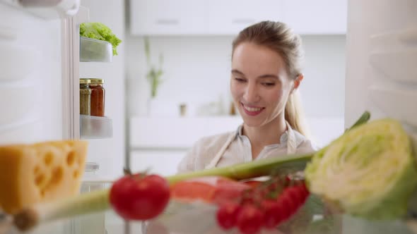 Woman picking some fruit and veggies from the fridge to make some healthy lunch.