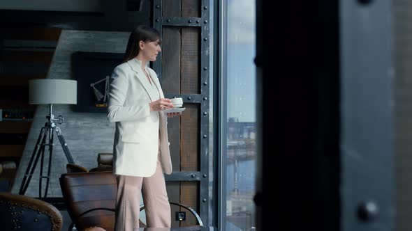 Thinking Woman Drinking Coffee at Panorama Window alt