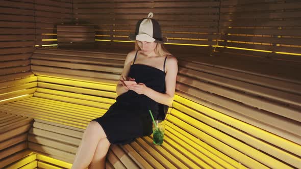 Blonde Woman in Sauna Surfing Internet and Having Rest