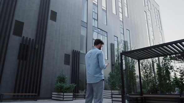Businessman Texting Standing at Modern Glass Office Building alt