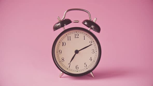 Black Alarm Clock on a Pink Background. 
