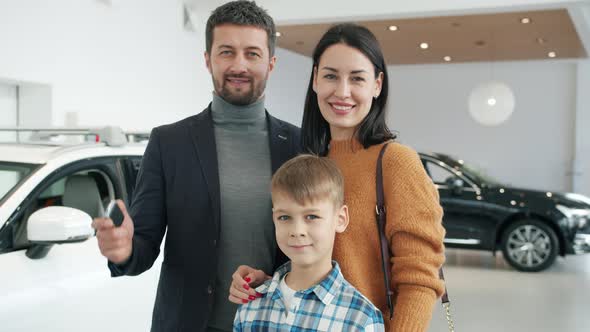 Portrait of Cheerful People Parents and Kid Standing Together in Automobile Showroom alt