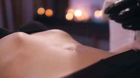 the specialist pours oil on the belly of a beautiful girl. body preparation for shugaring. Epilation